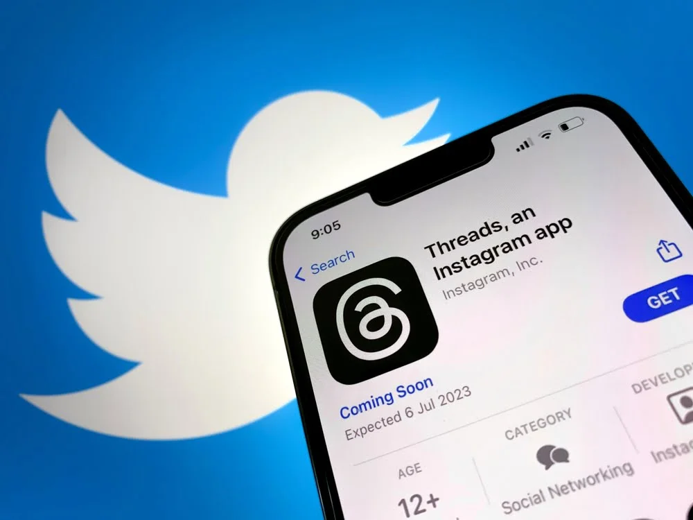 Threads: Meta's Instagram Launches New App to Rival Twitter 2 Meta Threads App on Phone, with Twitter logo in background. Twitter vs. Threads Rivalry