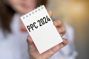 PPC written on a notepad, which is being held up by a woman.