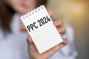 PPC written on a notepad, which is being held up by a woman.