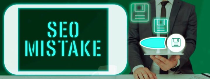 Image showing a person in a suit holding a tablet with the words 'SEO MISTAKE' displayed prominently on the screen. The background is green, and there are several floating icons of floppy disks, symbolizing data storage or saving, around the tablet.