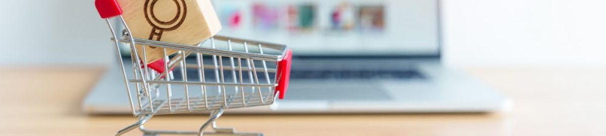 Shopping,Cart,With,Magnifying,Icon,Block,And,Laptop,Computer,With A miniature shopping cart with a red handle holding a wooden block featuring a magnifying glass icon. The cart is placed on a wooden surface in front of a blurred laptop screen, indicating an online shopping or e-commerce concept.